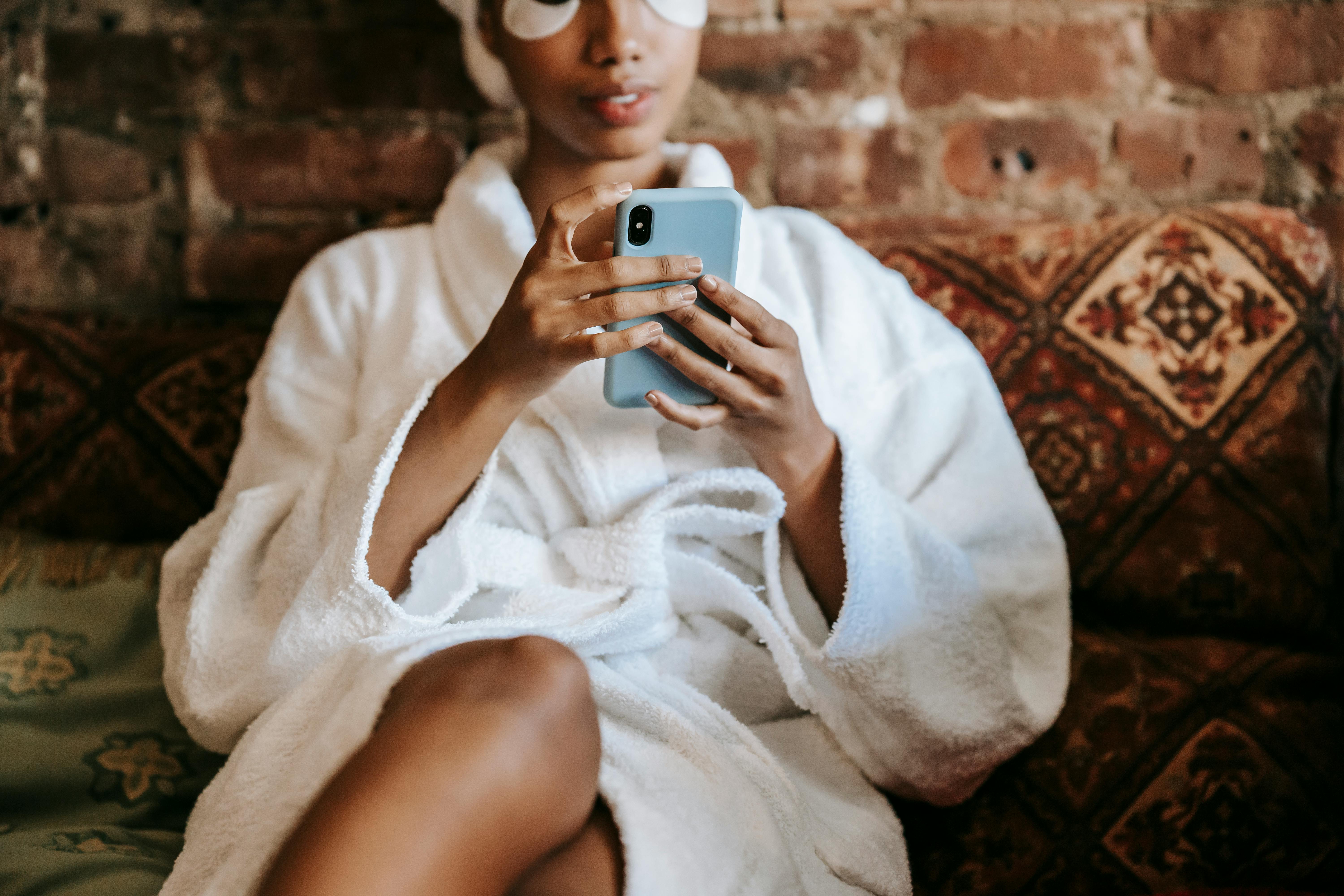 Picture of a woman scrolling on her phone in a bathrobe